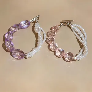 Primo piano di perle viola sfaccettate e bracciale di perle multistrato accessori moda.
