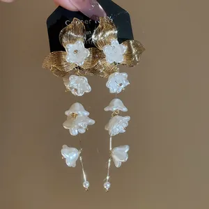 Detailed view of French golden flower earrings with white pearl bellflower tassels.