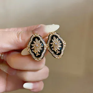 Detailed view of vintage flower earrings with black enamel and sparkling rhinestones