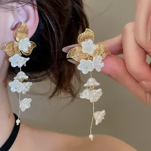 Close-up detail of French style flower tassel earrings with golden leaves and white pearls