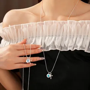 Elegant silver bead chain necklace with blue star and cross pendant worn by female model