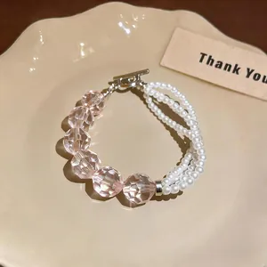 Primo piano del raffinato bracciale con perle rosa sfaccettate e perle bianche a più fili