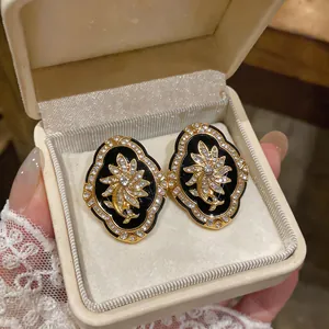 Detailed view of vintage palace style floral gold earrings with rhinestones in a gift box