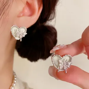Vue macro détaillée d'élégantes boucles d'oreilles cœur en argent avec papillon