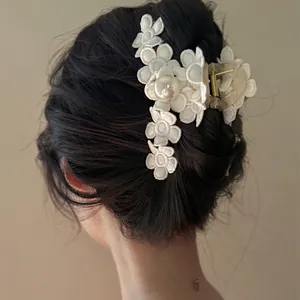 Vue arrière d'une élégante pince à cheveux fleur en dentelle blanche avec perle.