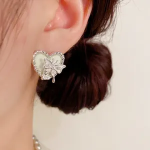 Vue détaillée de près d'une boucle d'oreille en forme de cœur avec un motif papillon sur l'oreille