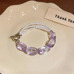 Vista dettagliata del bracciale a più fili di perle e perle di cristallo viola su un piatto.