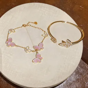 Detail of gold-tone bracelet and bangle featuring pearl and pink butterfly charms