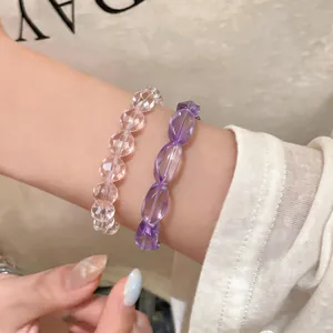 Primo piano di eleganti bracciali di perline sfaccettate trasparenti e viola indossati al polso