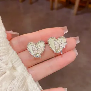 Gros plan de boucles d'oreilles en forme de cœur avec détails de papillon et de perles