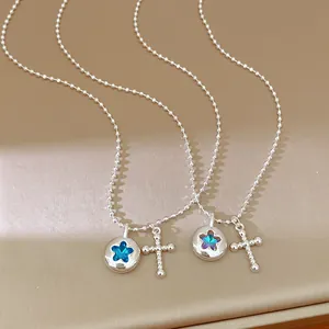 Detail view of silver-tone bead chain necklace with star and cross pendants