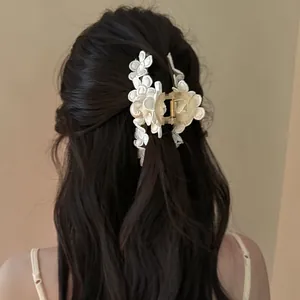Détail de dos d'une pince à cheveux vintage avec fleurs brodées blanches et perle élégante.