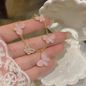 Close-up of an elegant gold butterfly bracelet with pink enamel and sparkling zircons