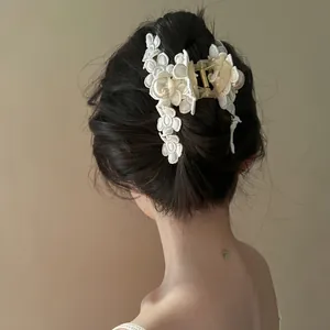 Détail d'une pince à cheveux vintage avec fleurs en dentelle et perles sur cheveux sombres