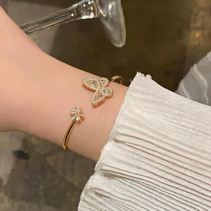 Elegant gold open cuff bracelet with butterfly and flower motifs, zircon and pearls