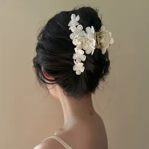 Détail d'une pince à cheveux vintage à fleurs avec une grande perle élégante.