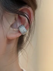 Detalle macro de un earcuff de plata minimalista con circonitas brillantes en una oreja.