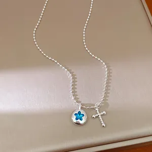 Detail shot of silver bead chain necklace with blue star rhinestone and cross pendants