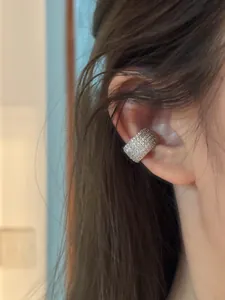 Detalle de un ear cuff minimalista de plata con circonitas brillantes en la oreja.
