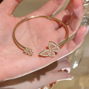 Close-up of gold-plated butterfly and flower bangle with pearls and zircon stones