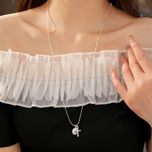 Detail view of a silver necklace with cross and star charms on a model.