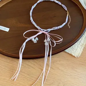Elegant pink ribbon bow necklace with beaded pearls and white lily of the valley charms