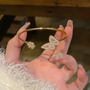 Elegant gold open bangle featuring a pearl-encrusted butterfly and flower detail.