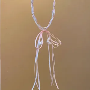 Sweet pink beaded pearl necklace with ribbon bow and lily of the valley charms.