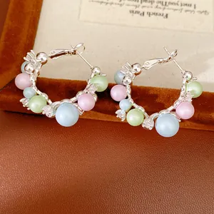 Close-up of elegant hoop earrings with pastel matte beads and sparkling rhinestones