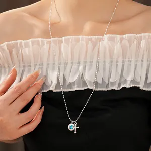 Detailed close-up of elegant silver cross necklace featuring a blue star pendant on model