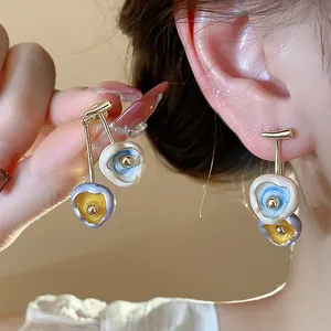 Detail showing texture of artistic 18k gold-plated enamel stud earrings worn on ear