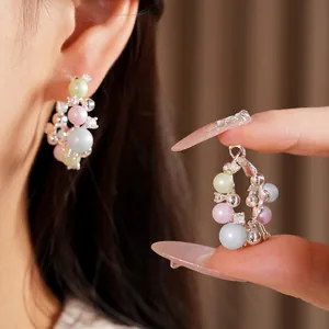 Detail shot of elegant hoop earrings with multi-colored pearls and small rhinestones.