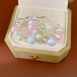 Detail of silver hoop earrings with pastel pearls and crystals in a green jewelry box.