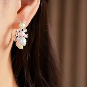 Close-up of elegant silver hoop earrings with pastel pearls and sparkling cubic zirconia.