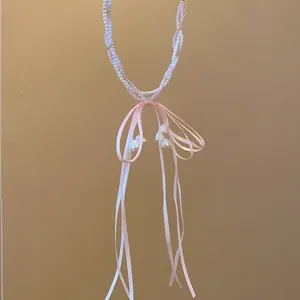 Detail view of a sweet pink ribbon bow necklace with beaded pearls and bellflower charms.