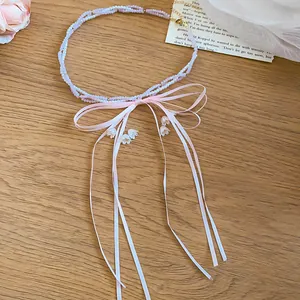 Close-up of pink beaded necklace with a delicate ribbon bow and flower charms