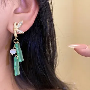 Eleganti orecchini pendenti a forma di bambù dorato con resina verde e strass