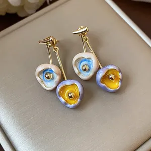 Detail view of 18k gold plated drop earrings featuring colorful dripping oil flower charms