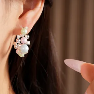 Detailed close-up view of elegant round pearl hoop earrings with crystal accents on model ear