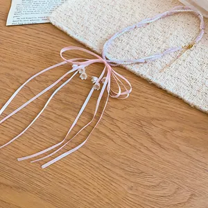 Exquisite detail of pink beaded pearl necklace featuring a large ribbon bow and lily charms