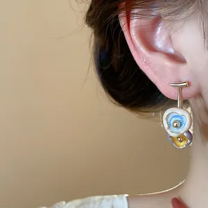 Macro view of 18k gold plated enamel flower stud earrings featuring silver needles