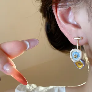 Close-up of artistic 18k gold plated earrings with colorful drip oil flower charms
