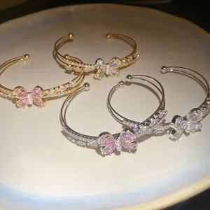 Detailed view of elegant butterfly zircon double-layered open bangles in gold and silver.