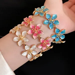 Bracciale vintage in metallo dorato con fiori in smalto colorato indossato al polso