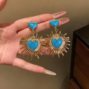 Orecchini a raggiera dorati con dettaglio cuore in smalto blu.