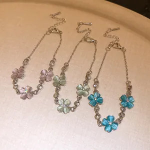 Dettaglio di tre braccialetti a fiori in pietra occhio di gatto rosa, verde e blu con catena