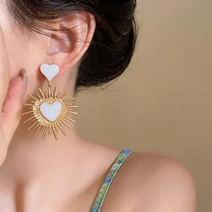 Primo piano di orecchini vintage a cuore con smalto bianco su una modella asiatica.