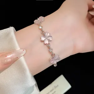 Dettaglio ravvicinato dei ciondoli a fiore in occhio di gatto rosa su bracciale