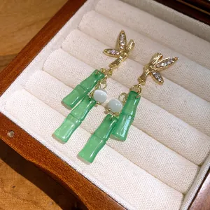 Dettaglio di orecchini di bambù con nappe in resina e strass in una confezione regalo
