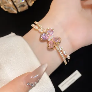 Close-up of an elegant double-layered gold bracelet featuring a pink zircon butterfly design